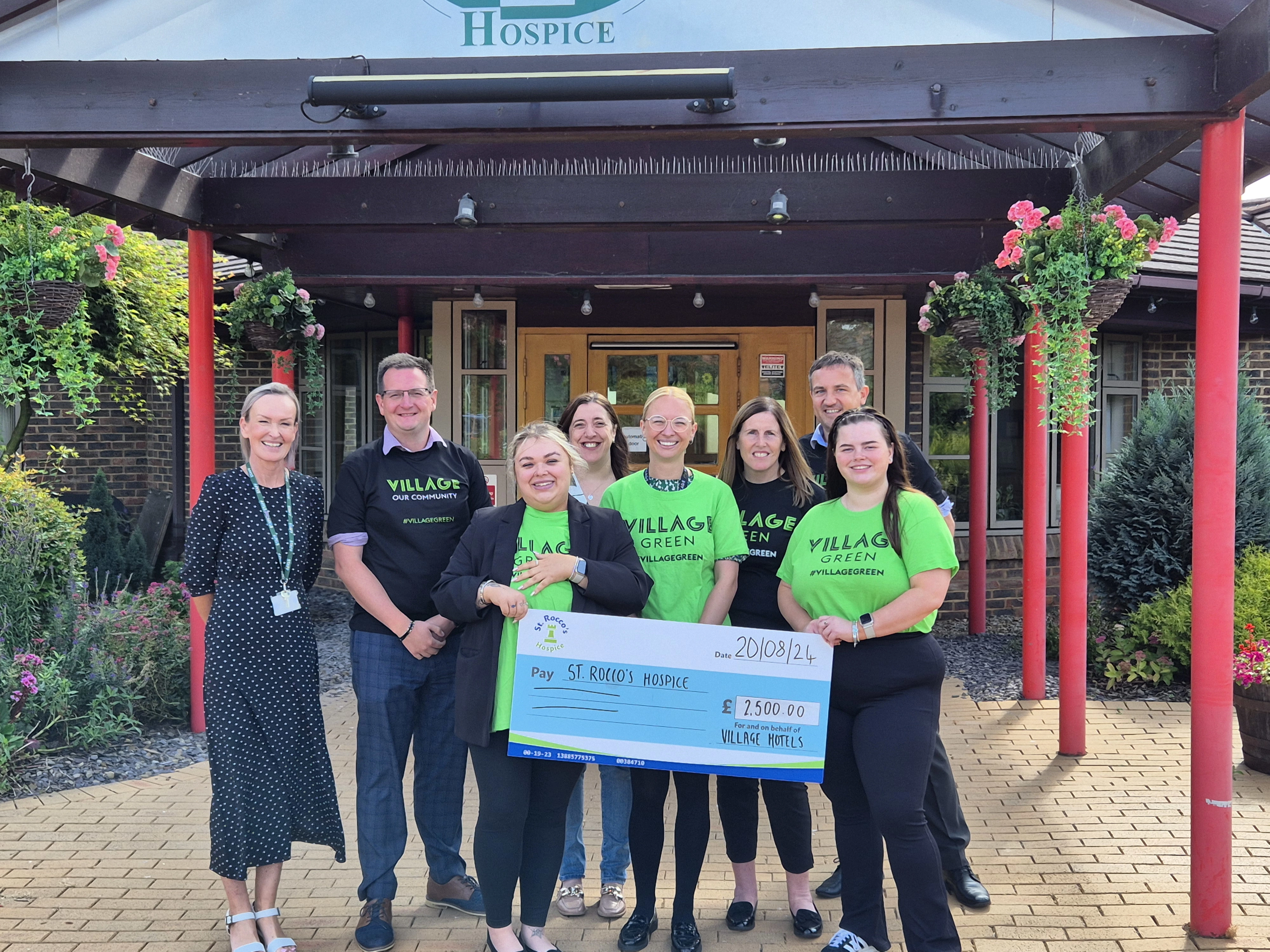 A photo of the Village Hotel staff and St. Rocco's staff holding a cheque